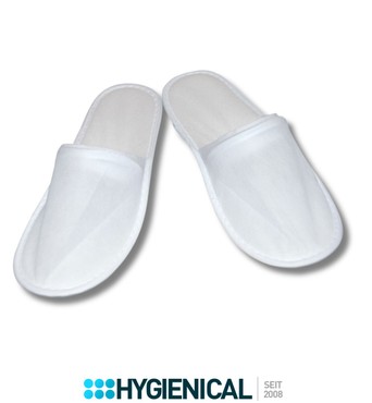 Paar weiße Einwegslipper, geschlossene Spitze, schräg von der Seite Paar weiße Einwegslipper, geschlossene Spitze, schräg von der Seite