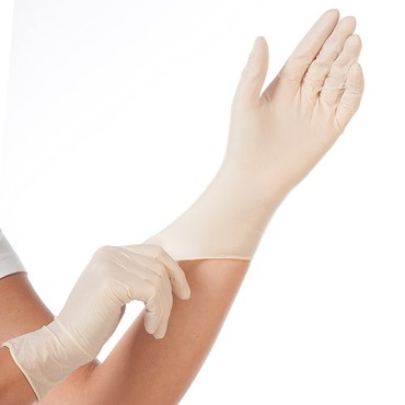 Hellbeiger Einweghandschuh wird über die Hand gestreift, Arm im Bild Hellbeiger Einweghandschuh wird über die Hand gestreift, Arm im Bild