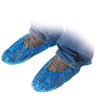 Füße in Jeans und Schuhen mit blauen Einweg-Überschuhen, Nahaufnahme