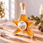 Sternflasche Weihnachtsflasche mit feinem Amaretto Likör mit Mandel- und Marzipannote in weihnachtlicher Deko-Szene mit Mandeln, Marzipanröllchen und einer Vanilleschote – perfekt als Adventsgeschenk, Mitbringsel oder Firmenpräsent