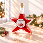 Granatapfel-Likör 20 % Vol. in weihnachtlicher Sternflasche Roter Granatapfel-Likör mit 20 % Vol. in einer Sternflasche auf hellem Naturholztisch mit Weihnachtssternen, Tannenzweigen und warmem Kerzenlicht.