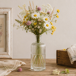 Designglasflasche als Vase mit Wiesenblumen Strukturierte 500-ml-Glasflasche als Vase mit Wiesenblumen in einer Vintage-Umgebung