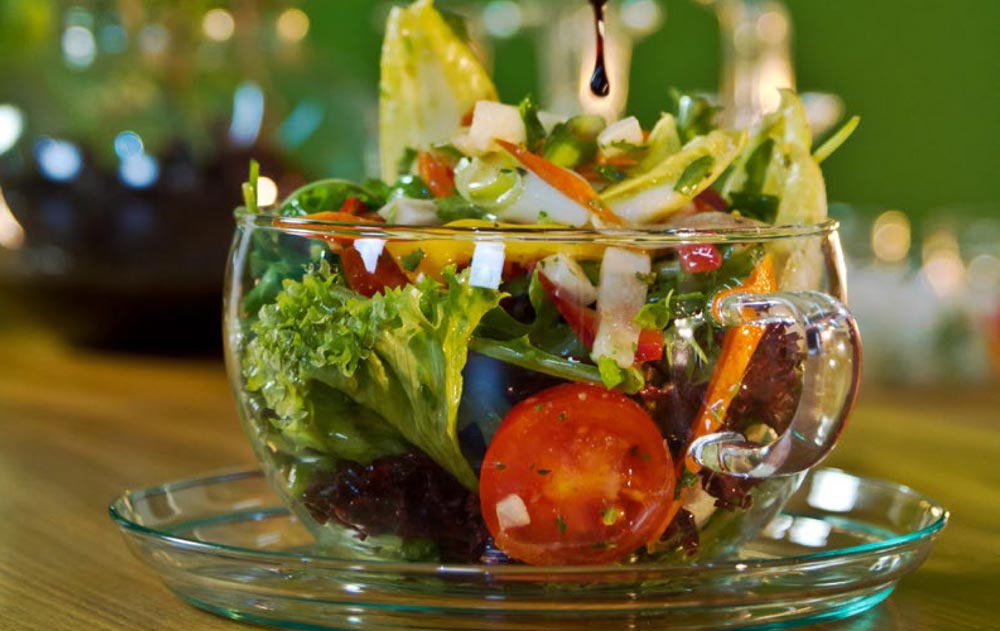 Glastasse mit gemischtem Salat auf einer Untertasse