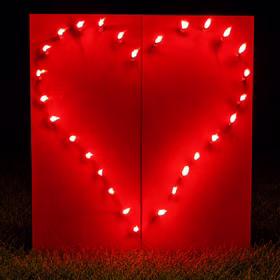 Lichterbild Brennendes Rotes Herz auf einer Wiese bei Dunkelheit.
