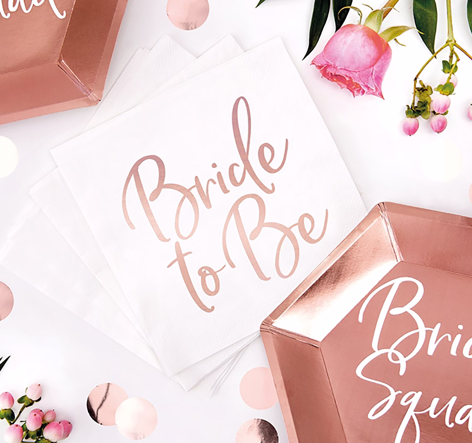 Weiße Servietten mit Bride to Be Aufdruck und roségoldene Bride Squad Pappteller als elegante JGA-Dekoration.