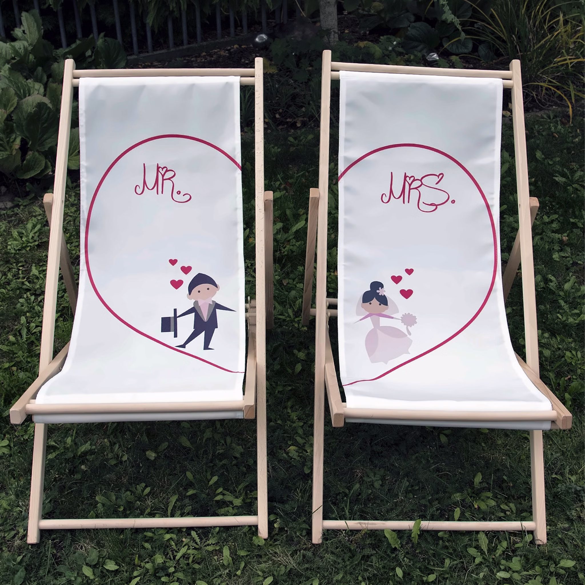 Hochzeits-Liegestuhl Mr. & Mrs. für Braut und Bräutigam Brautpaar individuelles Hochzeitsgeschenk 2 Liegestühle Geschenkidee zur Hochzeit Gastgeschenk Hochzeitsfeier Mr. & Mrs. Hochzeits-Liegestühle mit Classic Herz-Motiv nebeneinanderstehend auf grünem Rasen im Garten.