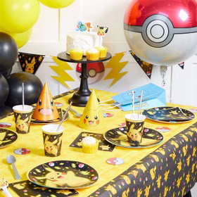 Gedeckter Pokémon Partytisch mit Pikachu-Tellern, Bechern, Servietten, Tischdecke, Wimpelkette, Partyhüten und Pokéball-Dekoration.