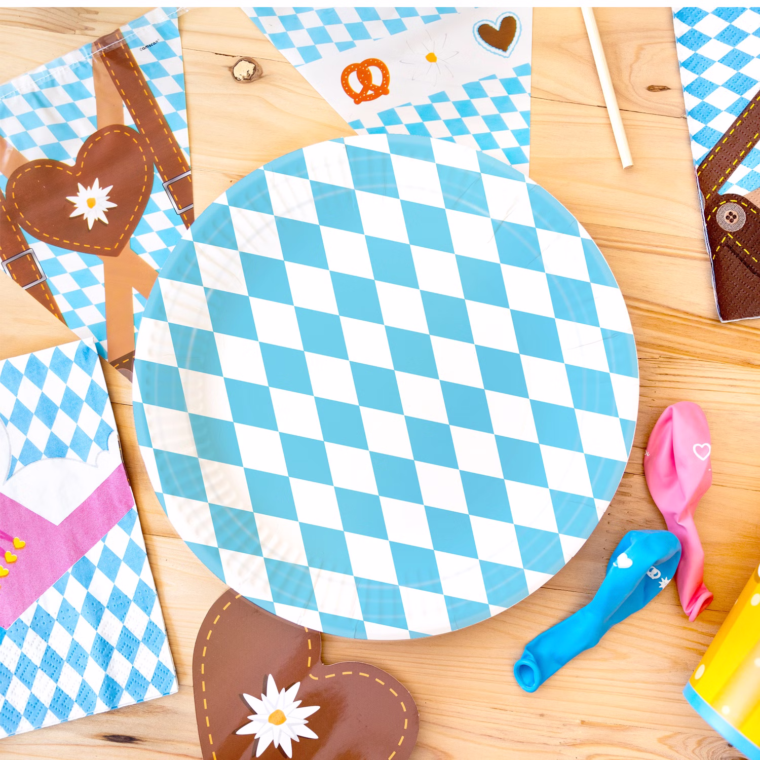 Runder Partyteller mit blau-weißem Rautenmuster auf einem Holztisch, umgeben von Servietten und weiterer Oktoberfest-Dekoration.