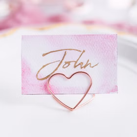 Tischkartenhalter Herzen Roségold 10 Stück Platzkartenhalter Hochzeit Geburtstag SALE Fotohalter Rosé Tischdeko Taufe Jugendweihe Kommunion Tisch-Deko Dekoration Zubehör Roségoldener Herzhalter präsentiert eine beschriftete Platzkarte als stilvolle Tischdekoration.