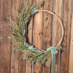 Rattan-Kranz Rund hängt an einer Holzwand und ist dekorativ mitTrockenblumen geschmückt.