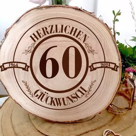 Runde Baumscheibe aus Holz mit Rinde und Gravur „Herzlichen Glückwunsch 60“, dekorativ auf einem Holztisch platziert.