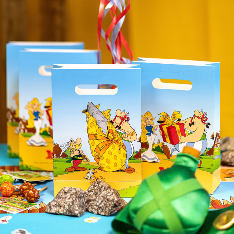 XXL Asterix & Obelix Geburtstag Party-Set Tisch-Deko 85-tlg. Part-Deko Kindergeburtstag Comic-Helden Dekoration gedeckter Tisch Hellblaue Geschenktüten mit Asterix- und Obelix-Motiven als dekorative Partyverpackung auf festlich gedecktem Tisch.