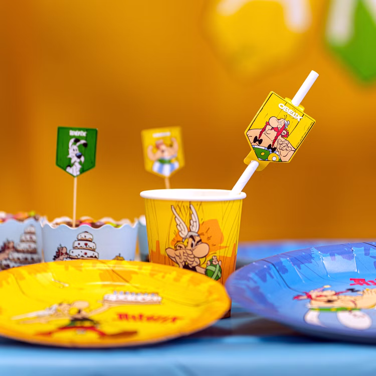 XXL Asterix & Obelix Geburtstag Party-Set Tisch-Deko 85-tlg. Part-Deko Kindergeburtstag Comic-Helden Dekoration gedeckter Tisch Asterix & Obelix Partybecher mit Comicmotiv auf Geburtstagstisch neben Tellern und Dekoration.