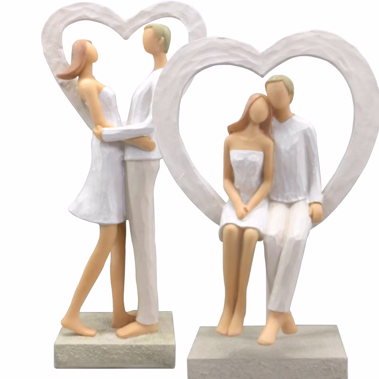 Brautpaar Figur Sitzend Liebe Weiß mit Herz Tischdeko Hochzeits-Deko Tisch-Deko Deko-Ideen Geschenkidee Braut & Bräutigam Zwei Brautpaar-Figuren im Herzrahmen, eine stehend umarmend, eine sitzend.