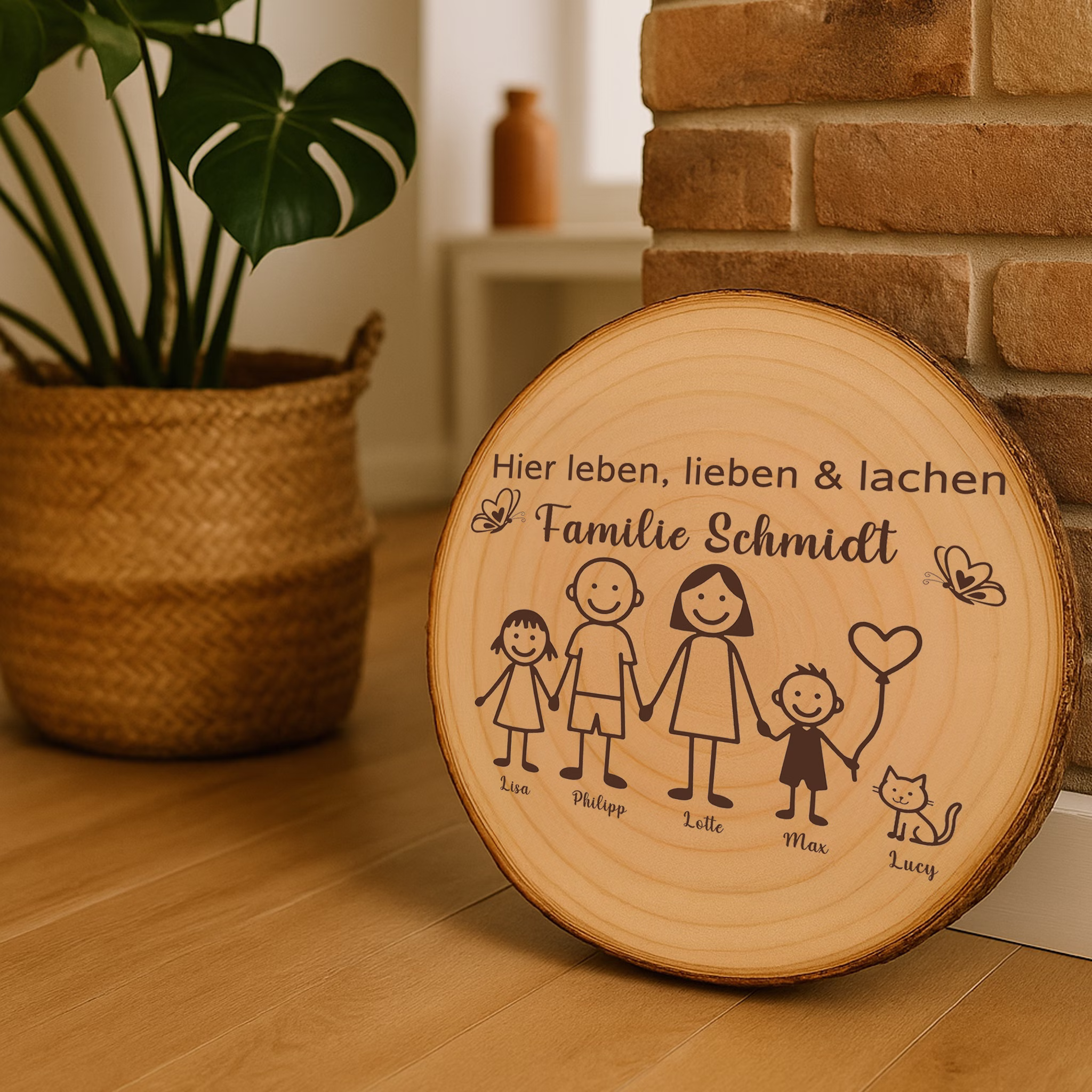 Baumscheibe 30 cm Familie Willkommensschild personalisiert mit Kindern & Katze Zuhause Deko & Geschenk Eingangsbereich Geschenk für Familie und Freunde Einzug Herzlich Willkommen Holzscheibe personalisiert Personalisierte Holzscheibe als Deko-Element in einem modernen Wohnraum neben einer Backsteinwand und einer Zimmerpflanze.