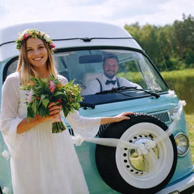 Autoschmuck Deko 2 Girlanden mit Blüten Weiß 180 cm Motorhaube Hochzeitsauto Wedding Car Organza-Girlande mit Rosenblüten Dekoration Braut mit Blumenstrauß steht vor einem hellblauen Hochzeitsauto, das mit weißen Organza-Girlanden geschmückt ist.