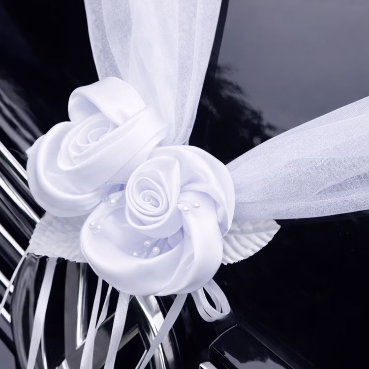 Autoschmuck Deko 2 Girlanden mit Blüten Weiß 180 cm Motorhaube Hochzeitsauto Wedding Car Organza-Girlande mit Rosenblüten Dekoration Nahaufnahme einer weißen Organza-Girlande mit zwei dekorativen Rosenblüten auf der Motorhaube eines schwarzen Autos befestigt.