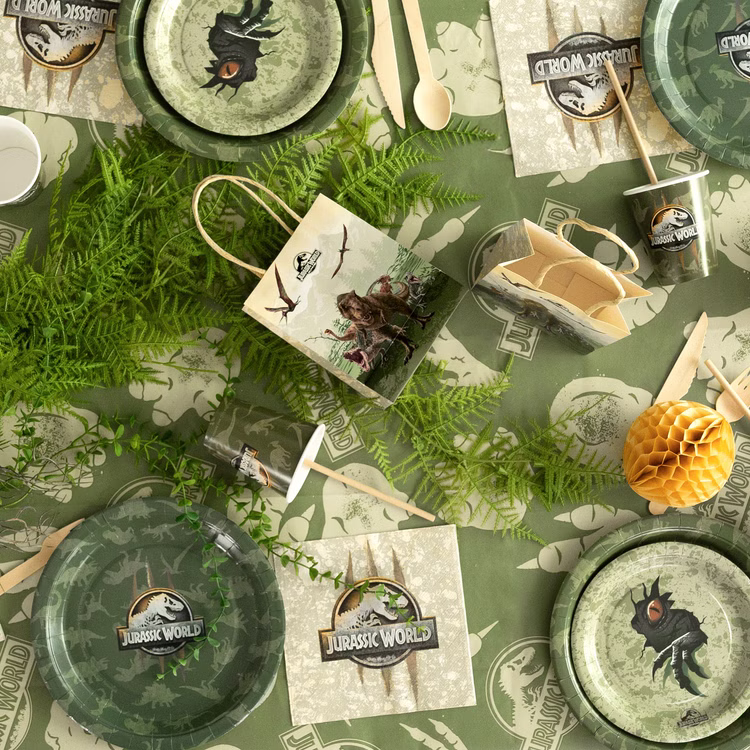 Jurassic World XXL Party-Set Dinosaurier Party-Deko 46-Teile T-Rex Geburtstag Saurier Lizenz-Party-Zubehör gedeckter Tisch Tisch-Deko Mottoparty Kindergeburtstag Geburtstag Draufsicht auf Jurassic World Partyzubehör mit Tellern, Bechern, Servietten, Geschenktüte und grüner Tischdecke.