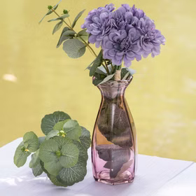 Glasvase Corolle 20 cm elegante Blumenvase Vintage Tisch-Deko Hochzeit Geburtstag Vase aus Glas festliche Tischdeko Wohnaccessoire Glasvase dekorativ Rosa Glasvase Corolle mit violetten Blumen und grünen Blättern auf einem hell gedeckten Tisch.