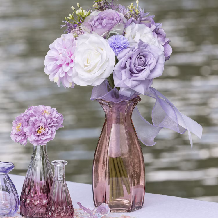 Glasvase Corolle 20 cm elegante Blumenvase Vintage Tisch-Deko Hochzeit Geburtstag Vase aus Glas festliche Tischdeko Wohnaccessoire Glasvase dekorativ Rosa Glasvase Corolle mit pastellfarbenem Blumenstrauß und Schleife als dekoratives Arrangement am Wasser.
