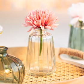 Glasvasen Verone 6er Tischvase Rosa Grün & Transparent Tisch-Deko Hochzeit Geburtstag Vase aus Glas festliche Tischdeko Wohnaccessoire Glasvase dekorativ Transparente Glasvase Verone mit rosa Blüte als Tischdeko auf geflochtener Unterlage in heller, festlicher Umgebung.