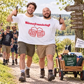 Doppel T-Shirt Männerfreundschaft Männertag Bollerwagen Zwei Männer tragen gemeinsam das weiße Doppel-T-Shirt „Männerfreundschaft“ mit Bierkrug-Motiv und sind am Männertag mit einem Bollerwagen unterwegs. Hinweis: KI generiertes Bild