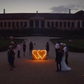 Lichterbild Brennendes Doppelherz mit Brautpaar und Hochzeitsgästen in der Abenddämmerung