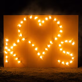 Lichterbild Brennendes Herz mit den Buchstaben K und S auf einer Wiese stehend bei Nacht.