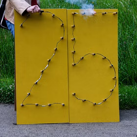 Lichterbild Brennende Zahl 25 Feuerbild Lichterbilder Geschenkidee Silberhochzeit Geburtstag Jubiläum Hochzeit Eine Person zündet die Zahl 25 auf einem Gehweg vor einem Feld.