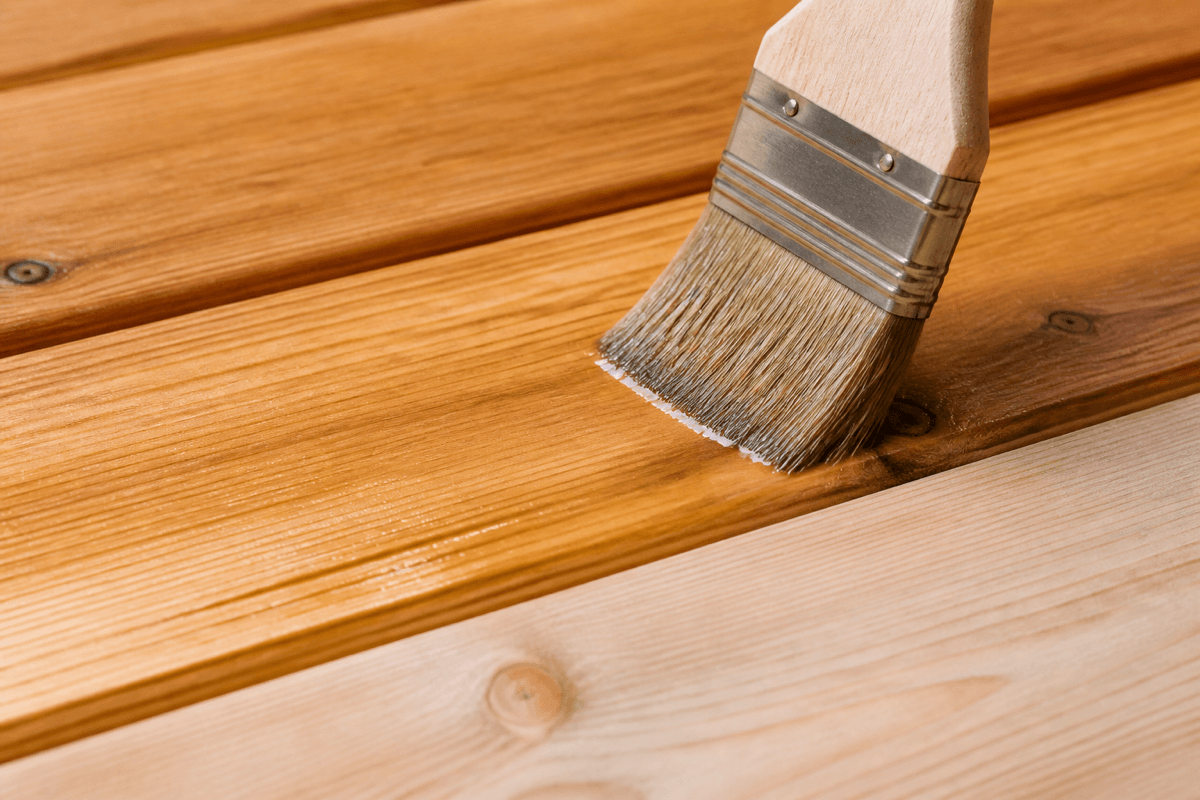 Caring for a wooden patio by applying natural wood oil with a brush