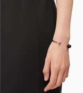 Brazalete moderno de acero inoxidable de Calvin Klein para mujer con cuenta negra y disco metálico plateado, KJ9RMF0401 Plata