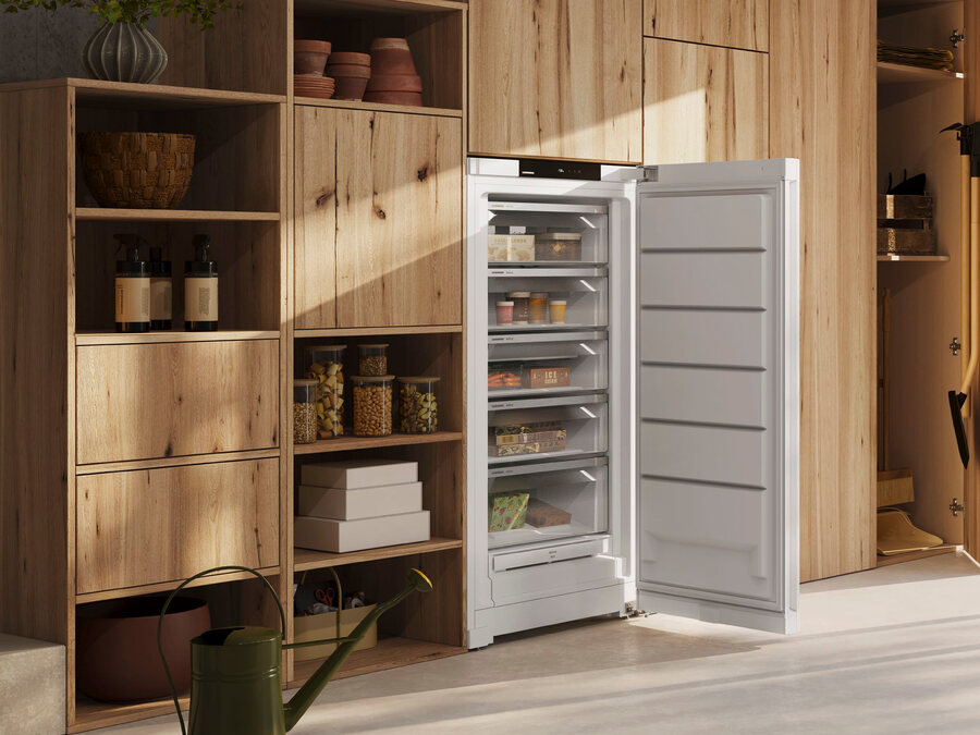 Geöffneter Liebherr Gefrierschrank mit gefüllten Schubladen in einem Hauswirtschaftsraum aus hellem Holz.