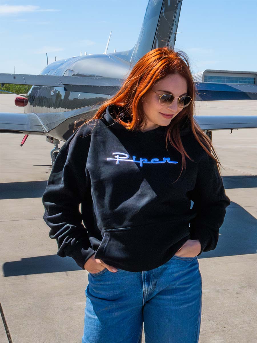 Eine rothaarige Frau in Sonnenbrille in einem Piper Hoodie,