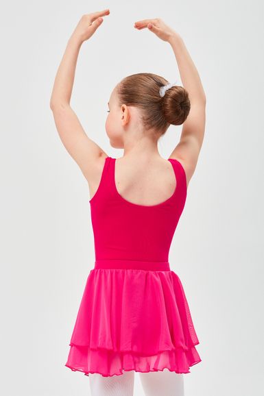 Ein junges Mädchen in einem rosa Ballettkleid steht mit über dem Kopf erhobenen Armen da und blickt von der Kamera weg.