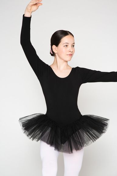 Eine junge Ballerina in einem schwarzen Ballettbody und Tutu posiert mit einem erhobenen Arm.