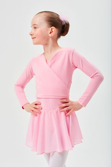 Ein junges Mädchen in einem hellrosa Ballett-Outfit steht mit den Händen in den Hüften und blickt zur Seite