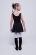 Ein junges Mädchen in einem schwarzen Ballett-Outfit und weißen Strumpfhosen steht mit dem Gesicht abgewandt. 4