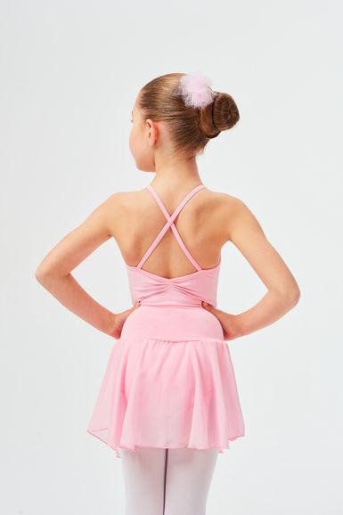 Ein Mädchen in einem rosa Ballett-Outfit steht mit den Händen in den Hüften und blickt von der Kamera weg.