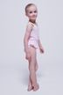 Ein junges Mädchen in einem hellrosa Ballettbody steht barfuß da 3