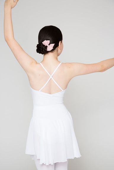 Eine Person in einem weißen Ballett-Outfit steht mit erhobenen Armen da