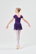 Eine junge Balletttänzerin in einem lila Ballettbody und Rock steht auf Spitze mit ausgestreckten Armen und dem Gesicht nach außen. 4