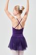 Eine junge Ballerina in einem lila Ballettbody und Rock steht mit erhobenen Armen da und blickt von der Kamera weg. 2