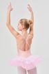 Ein Mädchen in einem rosa Ballett-Tutu steht mit erhobenen Armen und blickt von der Kamera weg. 2