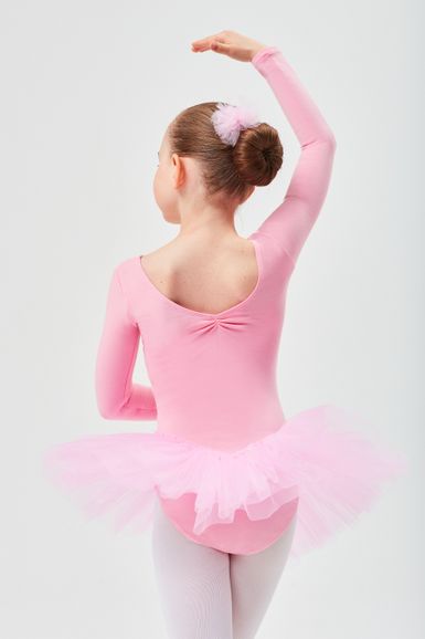 Junges Mädchen in einem rosa Ballett-Outfit und Tutu posiert mit einem erhobenen Arm und blickt von der Kamera weg.