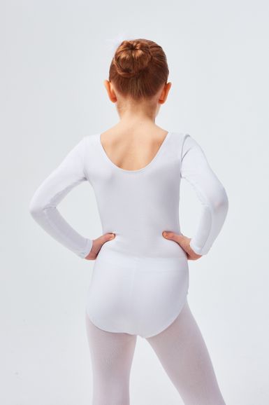 Ein junges Mädchen in einem weißen Ballettbody und Strumpfhosen steht mit den Händen in den Hüften und blickt von der Kamera weg.