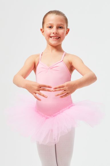 Ein junges Mädchen in einem rosa Ballett-Outfit posiert mit ausgestreckten Armen.