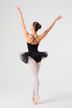 Eine Balletttänzerin in schwarzem Ballettbody und Tutu steht mit erhobenen Armen auf Spitze und blickt von der Kamera weg. 4
