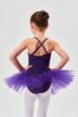 Ein junges Mädchen in einem lila Ballett-Tutu und weißen Strumpfhosen steht mit den Händen in den Hüften und blickt von der Kamera weg. 2