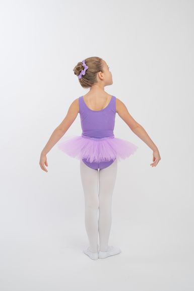 Ein junges Mädchen in einem lila Ballettbody und Tutu steht in einer Ballettpose mit dem Rücken zur Kamera.