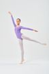 Eine Ballerina in einem lila Ballettbody und weißen Strumpfhosen führt eine Arabeskenpose aus. 3